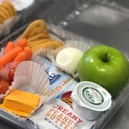 School lunch with cheese, apple, cookies and ranch dip.