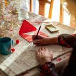 A woman writing a Christmas card on a wooden table